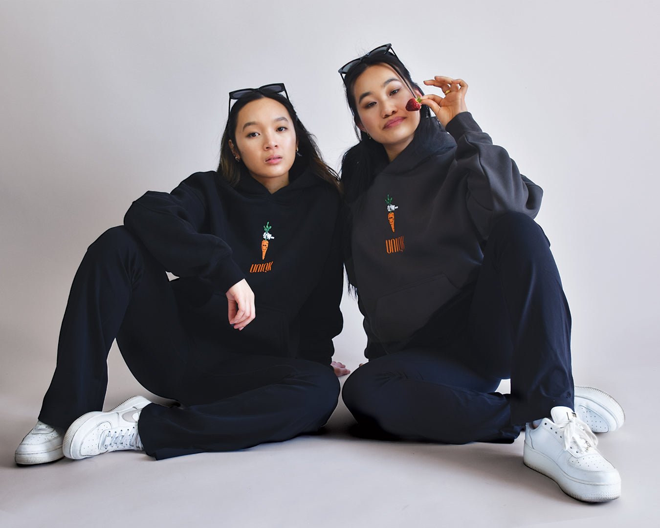 UNIQK 600 gsm Carrot Hoodie Black and Grey 100% Cotton Fleece Back Oversized Female Model sitting on Ground Front Embroidered Logo